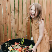 a pH tester in a compost bin filled with organic materials.