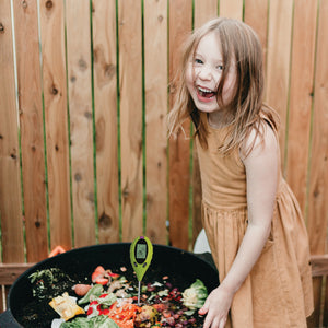 a pH tester in a compost bin filled with organic materials.
