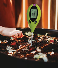a pH tester in a worm farm filled with organic materials.