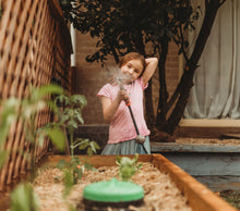 young child spraying water sprinkle in the garden