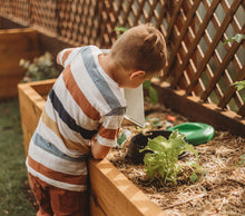 young boy pouring a bucket of water inside a worm buffet